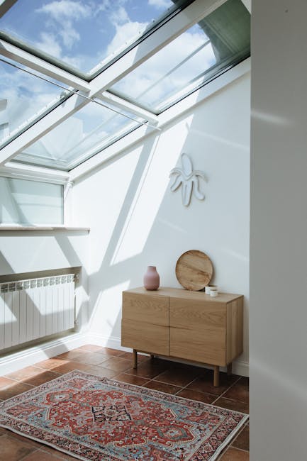 Bright attic room featuring skylight, dresser, and patterned carpet under sunlight.